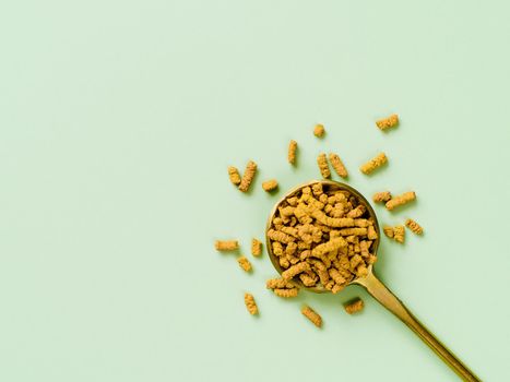 Buckwheat tea in spoon on light green background. Top view of healthy ku qiao or soba tea groats over green paper background. Minimal flat lay tartary buckwheat seeds. Copy space