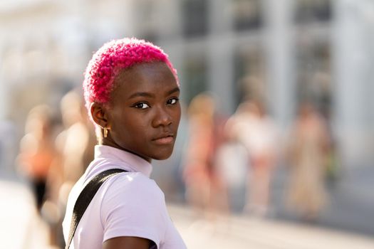 Portrait of a young african woman with short pink hair in a city