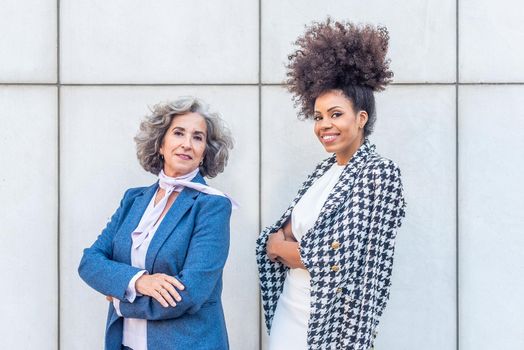 two female entrepreneurs posing for the camera with their arms folded, portrait view