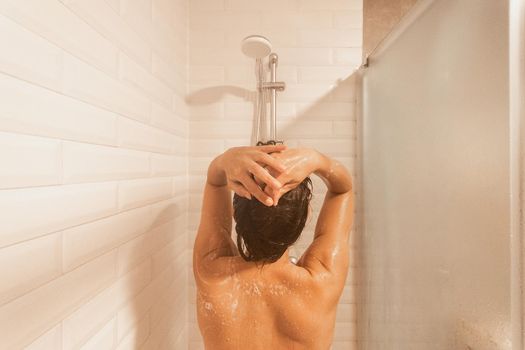 Rear view of a woman taking a shower in a hotel. Concept of hotel, hygiene.