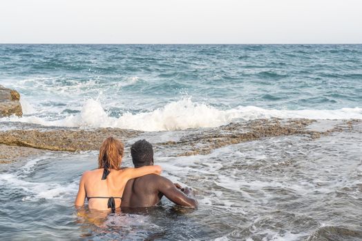 couple bathing in the sea embracing each other looking at the horizon, sea on the background