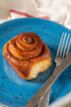 Freshly baked cinnamon roll on a blue porcelain plate