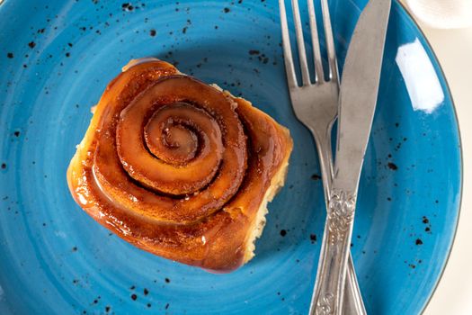 Freshly baked cinnamon roll on a blue porcelain plate