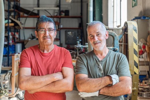 Two workers standing looking forward with folded arms, horizontal background