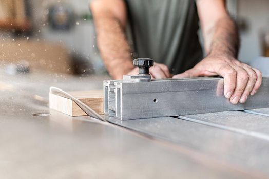 Person cutting a step diagonally with precision on a sliding table saw, close-up view