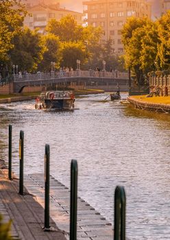 Antalya, Turkey - July 5, 2022: Touristic boat and gondola on the Porsuk River passing through the city center of Eskisehir