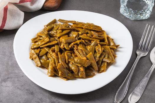 Green beans with olive oil on a white porcelain plate. Healthy eating concept