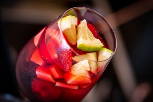 Glass of red Sangria and fruits on dark stone table