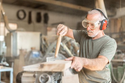 person working with a wooden board in safety equipment, horizontal blurred background