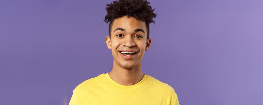 Close-up portrait of cheerful smiling man looking happy, express enthusiastic optimistic emotions, seeing something pleasant and interesting, standing purple background.