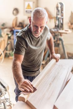 Standing person carefully sanding wood, blurred vertical background