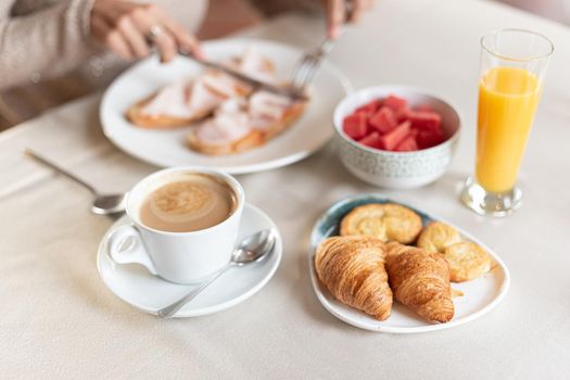 Selective focus in coffee and croissant for breakfast served for a woman at a table in a hotel dining room . Concept of breakfast in hotel.