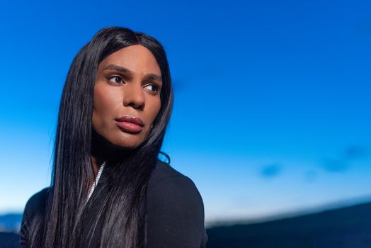 Portrait with copy space of a transgender female looking aside with distracted expression during sunset