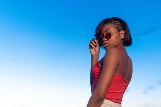 Portrait of copy space of a black young woman posing confident holding a sunglasses during dusk