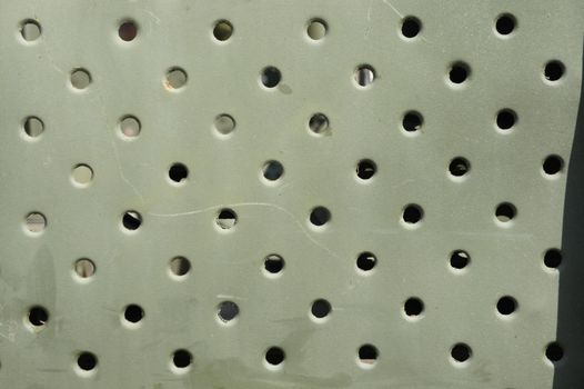 Lattice texture close up. Holes of grey metal plate with round regular holes texture background. Military Texture. Lattice construction on military vehicles in green protective colors