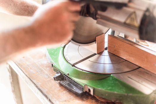 miter saw in motion, blurred hand in foreground, horizontal