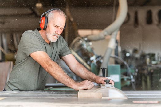 Carpenter cutting wood with precision on a sliding table saw, horizontal