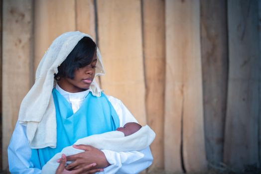 Photo with copy space of a african virgin mary representation holding a baby in arms in a crib