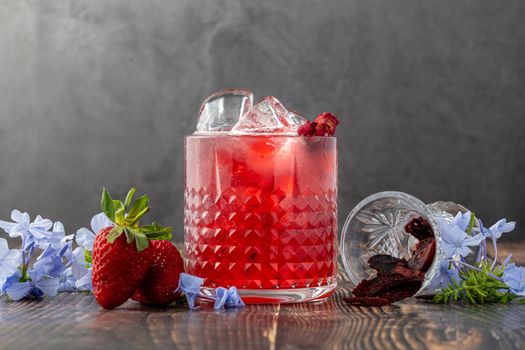 Iced cold strawberry tea with slices of dried strawberries on wooden table