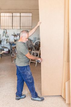 person standing holding a long MDF board, vertical