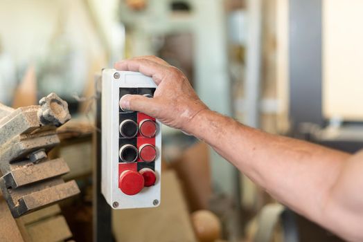 One person pushing a button in a wood factory, unfocused background, foreground