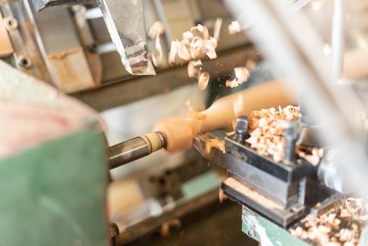 scraping wood turning a wooden baluster. Manufacturing process on a turning lathe, horizontal, blurred