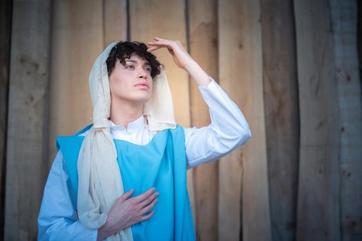 Portrait of an androgynous virgin mary gesturing while praying and gazing at the horizon