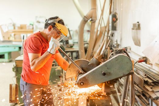 Adult man working with an iron cutter, sparks flying, horizontal