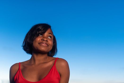 Portrait of a young african woman looking to the sky with happy expression during sunset