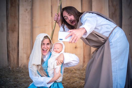 Biblical characters of the virgin mary and joseph taking a selfie while laughing and joking in a crib