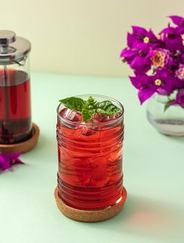 Freshly brewed iced red fruit tea on green table