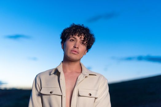 Close up portrait of a non binary caucasian male with gaze lost during dusk outdoors