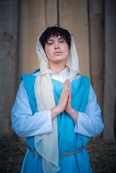 Vertical portrait of an androgynous virgin mary praying while facing the camera