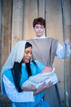 Vertical photo of nativity with transgender characters representing a scene where Mary holds Jesus in arms