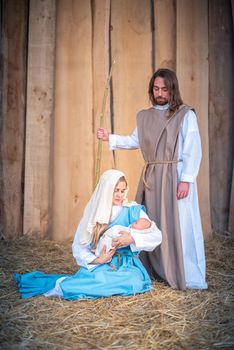 Vertical photo of a nativity scene with the virgin mary holding Jesus baby in a crib