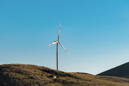 clean electricity producing wind turbine or windmill built on a windy mountain ridge