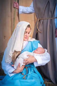 Vertical photo of virgin mary holding Jesus baby in a traditional nativity scene in a crib