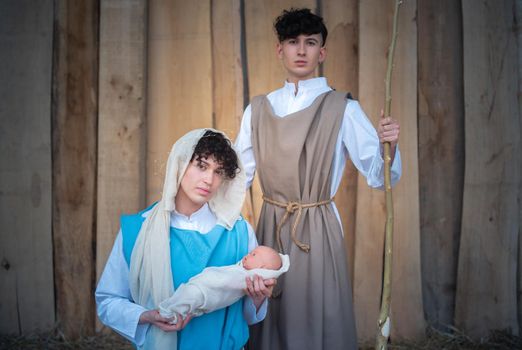 Nativity scene where the virgin mary holds the baby jesus next to joseph represented by androgynous people