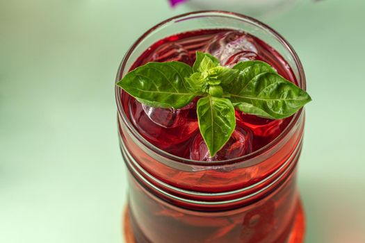 Freshly brewed iced red fruit tea on green table