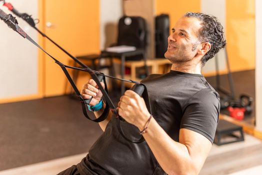 Sportsman doing exercise with trx fitness straps at gym. Concept of trx training.