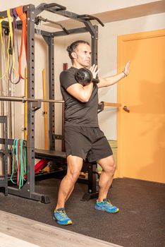 Sportsman doing shoulder press with kettlebell in gym. Concept of exercises with equipment in gym.