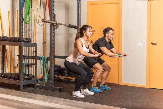 People doing squats without weighting exercise in gym. Concept of gym.