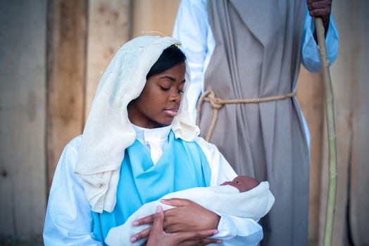 African virgin mary holding jesus baby in arms in a scene of the nativity next to a black Joseph