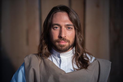 Man representing the biblical character of Joseph facing the camera with serene looking in a crib