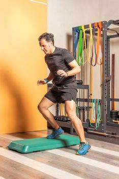 Sportsman doing lateral step up jumps in health club. Concept of exercises with equipment in health club.