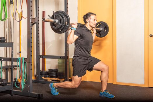 Sportsman doing squats with bellbar at gym. Concept of exercise in the gym.