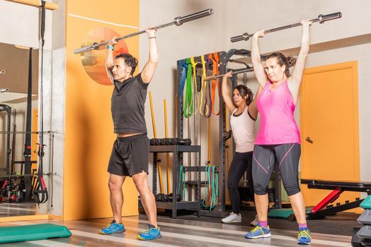 Athlete people doing press exercise with bar without weights in the gym. Concept of exercise with equipment in gym.