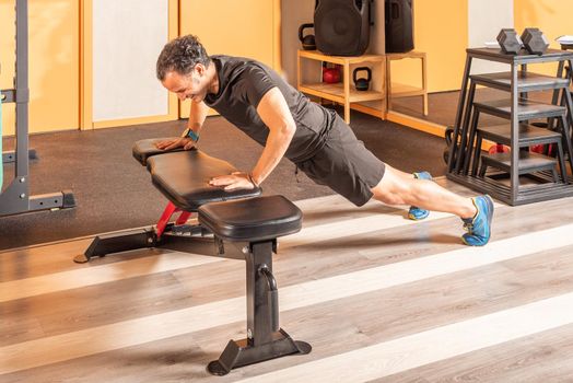 Sportsman doing push ups on bench in the gym. Concept of exercises in the gym.