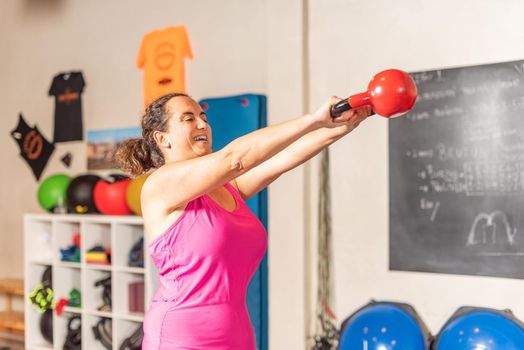 Woman doing kettlebell swing exercise in gym. Concept of exercise with equipment in gym.