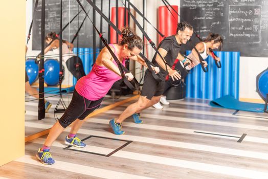 People doing back exercises with trx fitness straps at gym. Concept of trx exercises.